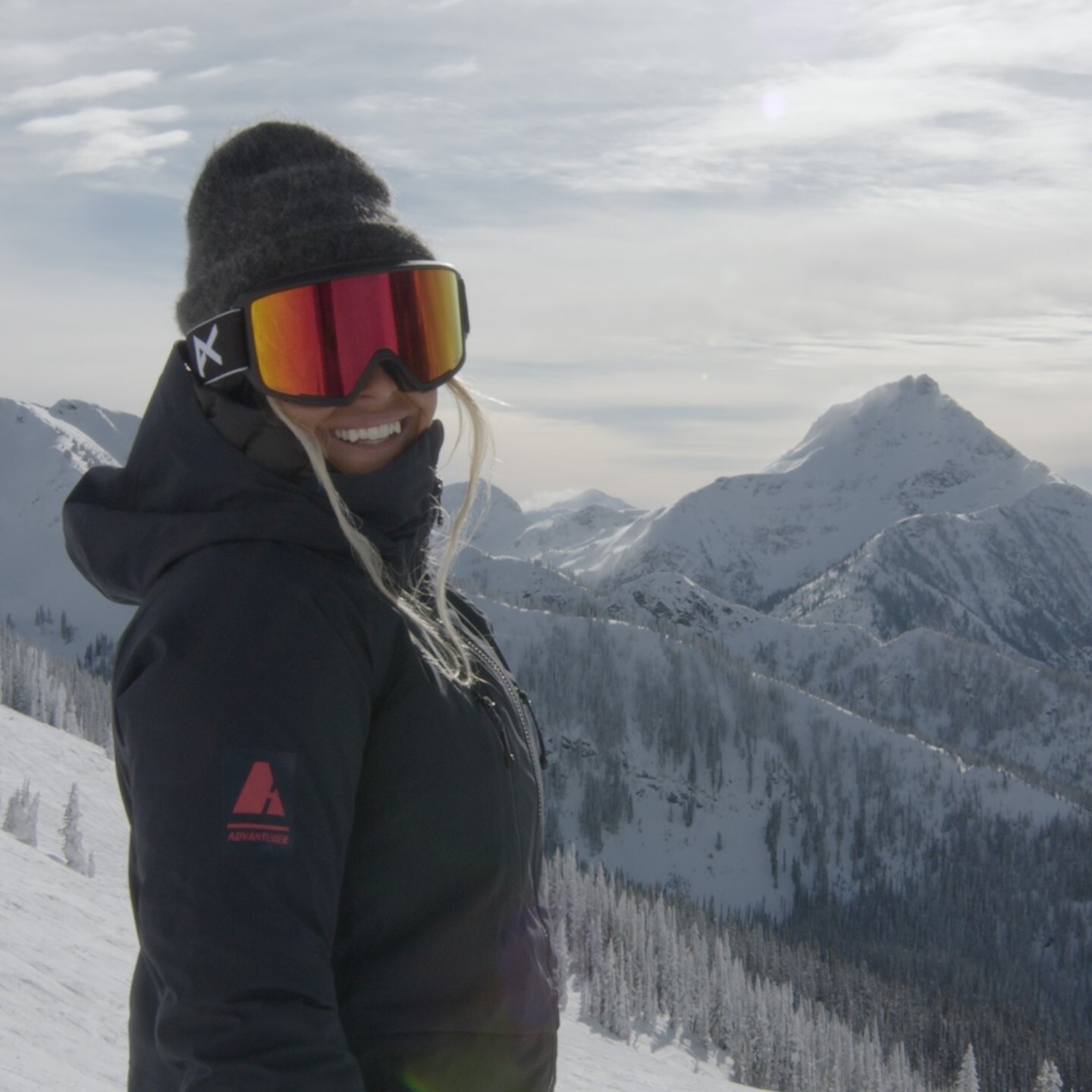 woman facing camera wearing advanturer jacket on mountain