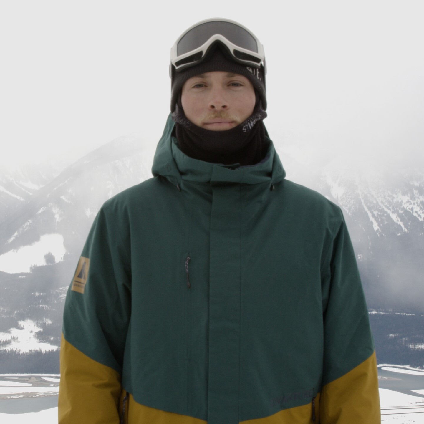 man facing camera wearing advanturer jacket on mountain